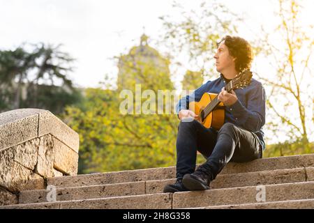 Homme d'âge moyen jouant de la guitare espagnole sur quelques escaliers dans la rue Banque D'Images