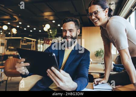 Deux personnes en voyage d'affaires prenant un appel vidéo dans un espace de travail commun.Deux hommes d'affaires souriants tout en communiquant avec leurs partenaires.Joyeux jeune Banque D'Images