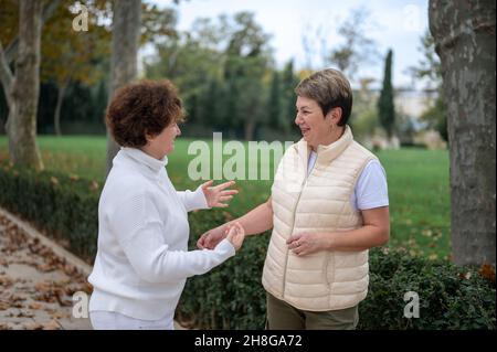 Deux femmes âgées à l'extérieur.Deux femme de sureau parlant.Deux vieux amis bavardent dans le parc.Des femmes d'âge moyen souriantes parlent à l'extérieur Banque D'Images