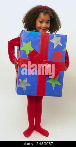 Une fille portant une boîte en carton emballée de cadeau. Banque D'Images