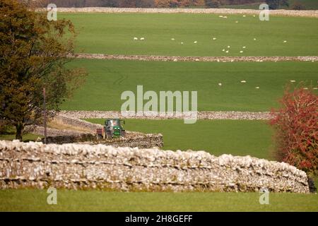 PENRITH campagne, Shap Un tracteur John Deere SERPENTE LENTEMENT À TRAVERS LES VOIES DE CAMPAGNE DU MUR DE PIERRE Banque D'Images