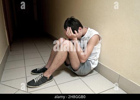 Triste jeune homme sur le plancher de la maison Banque D'Images