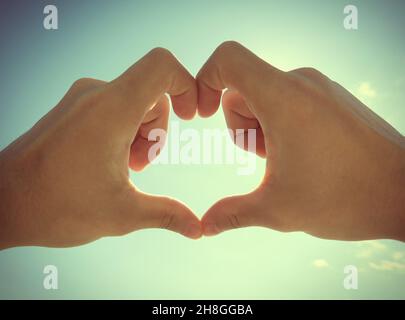 Photo tonifiée des mains en forme de coeur sur fond de ciel Banque D'Images