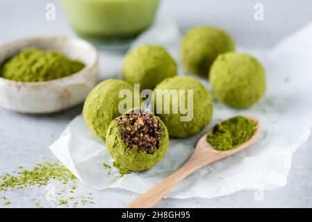 Boules d'énergie de thé vert matcha crues avec des dattes et des noix sur papier parchemin, bonbons manquant une morsure Banque D'Images