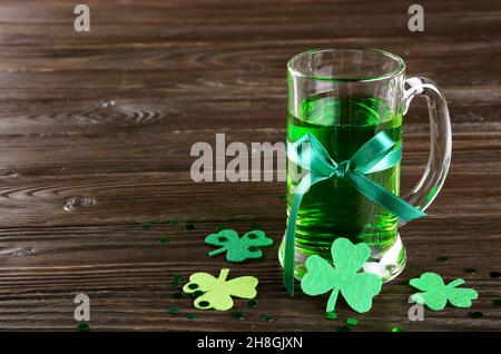 La journée de St Patricks est agrémentée d'une pinte de bière verte sur une table en bois avec des shamrocs en feutre faits à la main. Espace-copie Banque D'Images