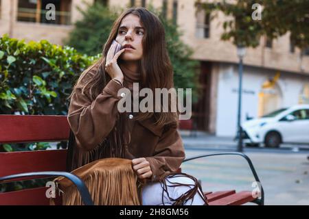 Elle s'est assise sur un banc et a appelé avec son téléphone Banque D'Images