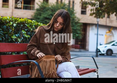 Elle était assise sur un banc et cherchait son téléphone Banque D'Images