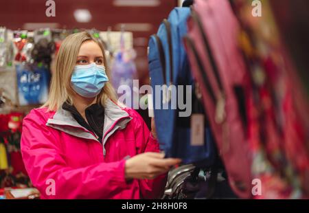 Femme dans le masque médical est de choisir le sac à dos pour enfant pour l'école. Banque D'Images