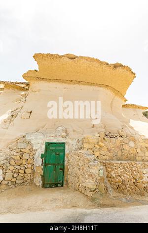 Pièce de coupe de roche avec porte verte sur les casseroles de sel, Gozo Banque D'Images