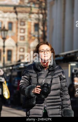 Saint-Pétersbourg, Russie - Mars 2021.Une femme heureuse en vacances en train de photographier avec un appareil photo dans la rue de la ville Banque D'Images