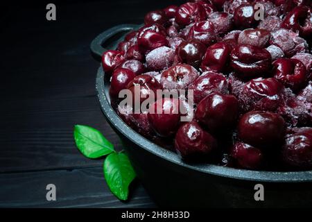 Beaucoup de cerise surgelée sans bâtons dans le bol sur fond noir en bois.vitamines et une alimentation saine Banque D'Images