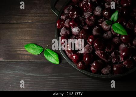 Beaucoup de cerise surgelée sans bâtons dans le bol sur fond noir en bois.vitamines et une alimentation saine.Copier l'espace Banque D'Images