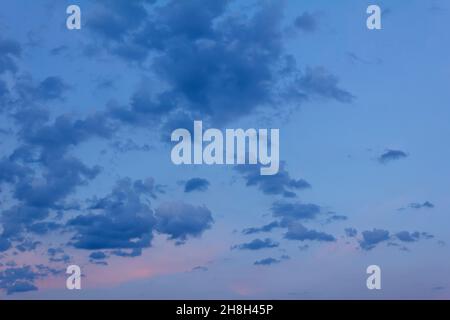 Nuages bleu foncé après le coucher du soleil avec les derniers rayons de soleil orange rouge, texture d'arrière-plan douce et nuageux. Banque D'Images