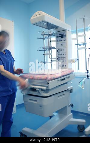 Le travailleur médical reste à côté de l'incubateur de bébé à l'hôpital. Banque D'Images