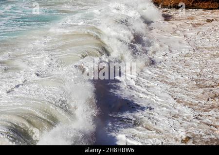 Seafoam avec des vagues qui frappent le rivage avec un jet laiteux blanc.Image de stock. Banque D'Images