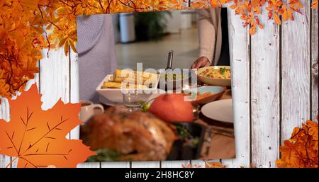 Image numérique composite des personnes ayant de la nourriture à la fête de Thanksgiving et les feuilles d'automne, l'espace de copie Banque D'Images