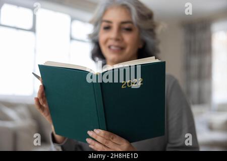 Gros plan de la femme mature tenant le Journal du nouvel an 2022 à la maison Banque D'Images