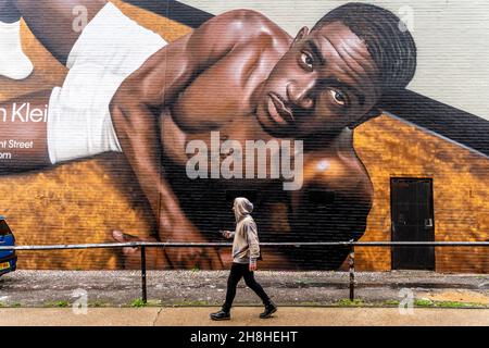 Un jeune homme passe devant un certain Street Art/Graffiti, Shoreditch, Londres, Royaume-Uni. Banque D'Images