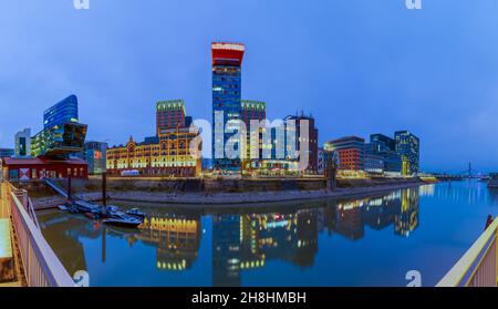 Panorama en soirée du Medienhafen à Düsseldorf avec vue sur le quai avec différentes chaînes d'hôtels situées telles que Melia, Marriott et Hyatt Banque D'Images