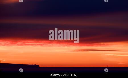 Lever de soleil à l'est depuis Mumbles Head, au-dessus de la mer jusqu'à l'horizon lointain et les nuages colorés rouge et orange par le soleil tôt le matin. Banque D'Images