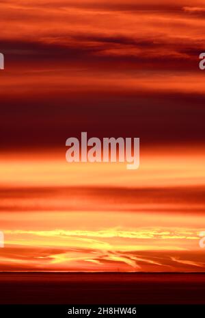 Lever de soleil à l'est depuis Mumbles Head, au-dessus de la mer jusqu'à l'horizon lointain et les nuages colorés rouge et orange par le soleil tôt le matin. Banque D'Images