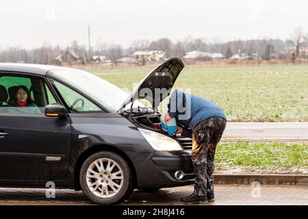 Riga, Lettonie, le 2 janvier 2021 : le conducteur de la voiture remplit le liquide de lave-glace bleu non givré dans le réservoir de la voiture Banque D'Images