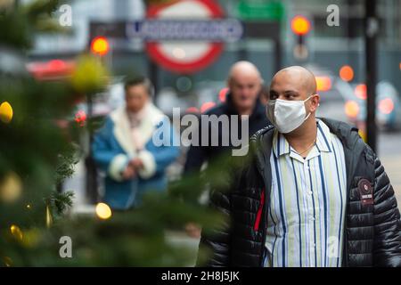 Londres, Royaume-Uni.30 novembre 2021.Un homme passe les arbres de Noël devant Harvey Nichols à Knightsbridge le premier jour où des revêtements de visage sont de nouveau nécessaires dans les magasins, suite aux nouvelles mesures du gouvernement britannique pour tenter de freiner la propagation du coronavirus suite à la détection de la variante Omicron.Credit: Stephen Chung / Alamy Live News Banque D'Images