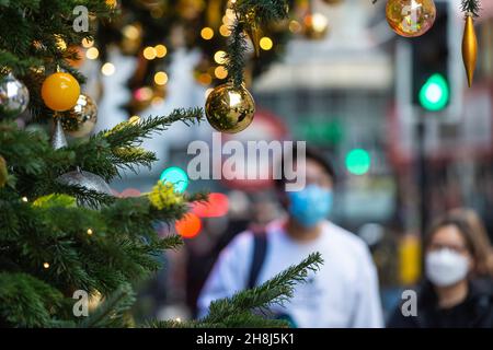 Londres, Royaume-Uni.30 novembre 2021.Un couple passe devant les arbres de Noël à Harvey Nichols à Knightsbridge le premier jour où des revêtements de visage sont de nouveau nécessaires dans les magasins, suite aux nouvelles mesures du gouvernement britannique pour tenter de freiner la propagation du coronavirus après la détection de la variante Omicron.Credit: Stephen Chung / Alamy Live News Banque D'Images