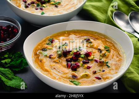 Bols de soupe de citrouilles rôties au Maroc : soupe de potiron rôtie garnie de feuilles de menthe, de graines de grenade et de pistaches hachées Banque D'Images