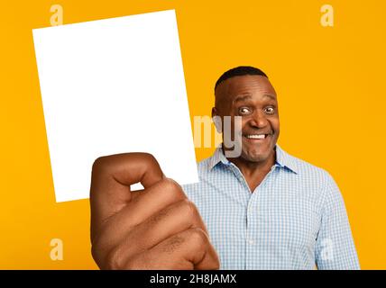 Joyeux homme afro-américain d'âge moyen montrant une carte vierge Banque D'Images