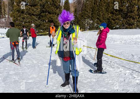 L'artiste local Bruce Macintosh habillé en costume portant une perruque violette vif donne l'atmosphère au Chama Chile ski Classic dans les montagnes de San Juan, aux États-Unis. Banque D'Images