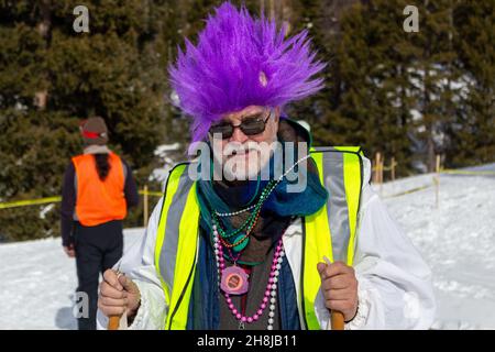 L'artiste local Bruce Macintosh habillé en costume portant une perruque violette vif donne l'atmosphère au Chama Chile ski Classic dans les montagnes de San Juan, aux États-Unis. Banque D'Images