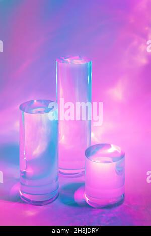 trois podiums en verre transparent sur fond rose pastel Banque D'Images