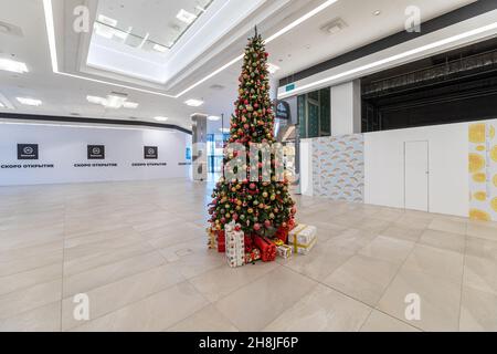Minsk, Bélarus - 25 novembre 2021 : photo d'un arbre de Noël vert avec des boules lumineuses et des cadeaux dans des boîtes dans un centre commercial.Noël et nouvel an Banque D'Images