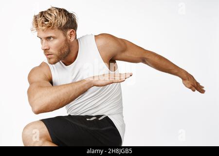 Portrait d'entraînement sportif, étirement et soulèvement des jambes, échauffement avant le jogging, faire des exercices de sport, fond blanc Banque D'Images