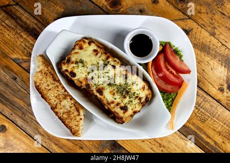 lasagnes sur une assiette blanche avec pain et salade, viande et végétarien Banque D'Images