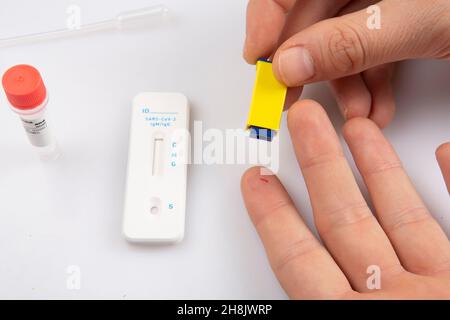 injection isolée d'une main avec un lancet prenant un échantillon de sang du doigt et un blanc rapide express antigène antobody coronavirus covid-19 pandémie t Banque D'Images