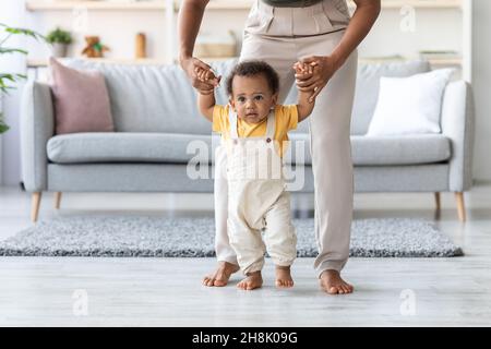 Mignon enfant amérindien mignon faire les premiers pas avec l'aide de la mère Banque D'Images