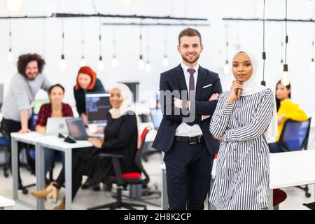 Deux collègues multiethniques dans un espace de bureau moderne. Groupe de personnes travaillant en arrière-plan concept de diversité et de réussite. Banque D'Images