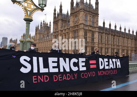 Londres, Royaume-Uni.30 novembre 2021.Les manifestants tiennent une bannière disant « Silence = Death slogan » aux chambres du Parlement du pont de Westminster pendant la manifestation.les militants exigent que le gouvernement britannique suspende les règles de propriété intellectuelle qui bloquent la production de vaccins dans le monde entier.Crédit : SOPA Images Limited/Alamy Live News Banque D'Images