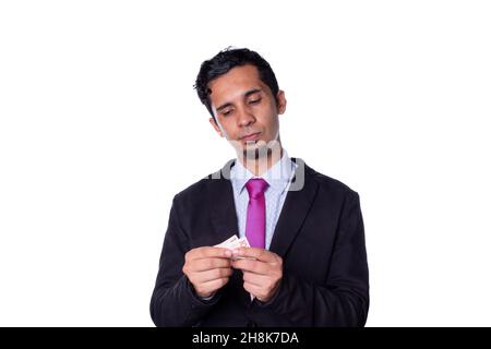 Homme d'affaires comptant de l'argent avec ses mains.Jeune latin adulte jeune homme avec un regard sérieux regardant l'argent liquide, isolé sur tout fond blanc. Banque D'Images