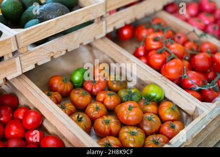 Récolte de tomates mûres de différentes variétés en caisses sur le comptoir Banque D'Images