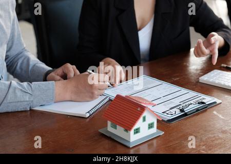 L'agent immobilier a parlé des termes de l'accord d'achat de maison, le client signe les documents pour faire le contrat légalement, les ventes de maison et la maison Banque D'Images