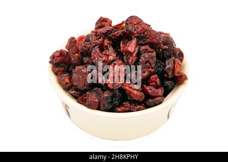 Canneberge rouge savoureuse (séchée) dans une tasse blanche isolée sur fond blanc avec passe-cheveux.Mise au point sélective. Banque D'Images