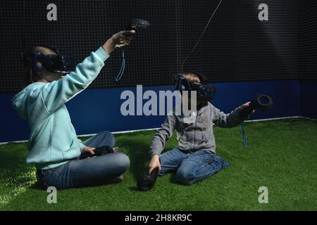 Deux enfants bénéficiant de la technologie VR, garçon et fille portant un casque de réalité virtuelle et jouant dans le simulateur de travail Banque D'Images