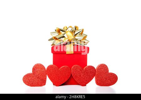 Boîte cadeau rouge avec noeud doré et 4 coeurs isolés sur fond blanc.Concept de fêtes comme Noël, mariage, Saint Valentin, ou autre happ Banque D'Images