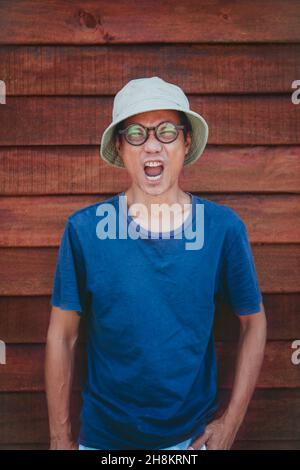 homme asiatique portant des vêtements chapeau agissant wow avec visage drôle Banque D'Images