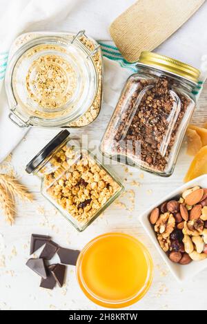 Vue de dessus des bocaux pleins d'avoine et divers granola croquant - nature, fruits secs, noix et chocolat.Concept de repas de grande qualité. Banque D'Images