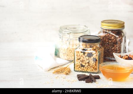 Bocaux pleins d'avoine et divers granola croquant - simple, fruits secs, noix et chocolat.Concept de repas de grande qualité.Copier l'espace. Banque D'Images