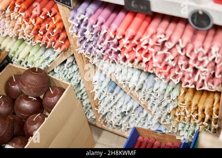 De nombreuses bougies multicolores colorées couleur bâton de paraffine couleurs pastel disposées dans des étagères couchée sur un abri et triées par couleur dans un magasin de bougies maison St Banque D'Images